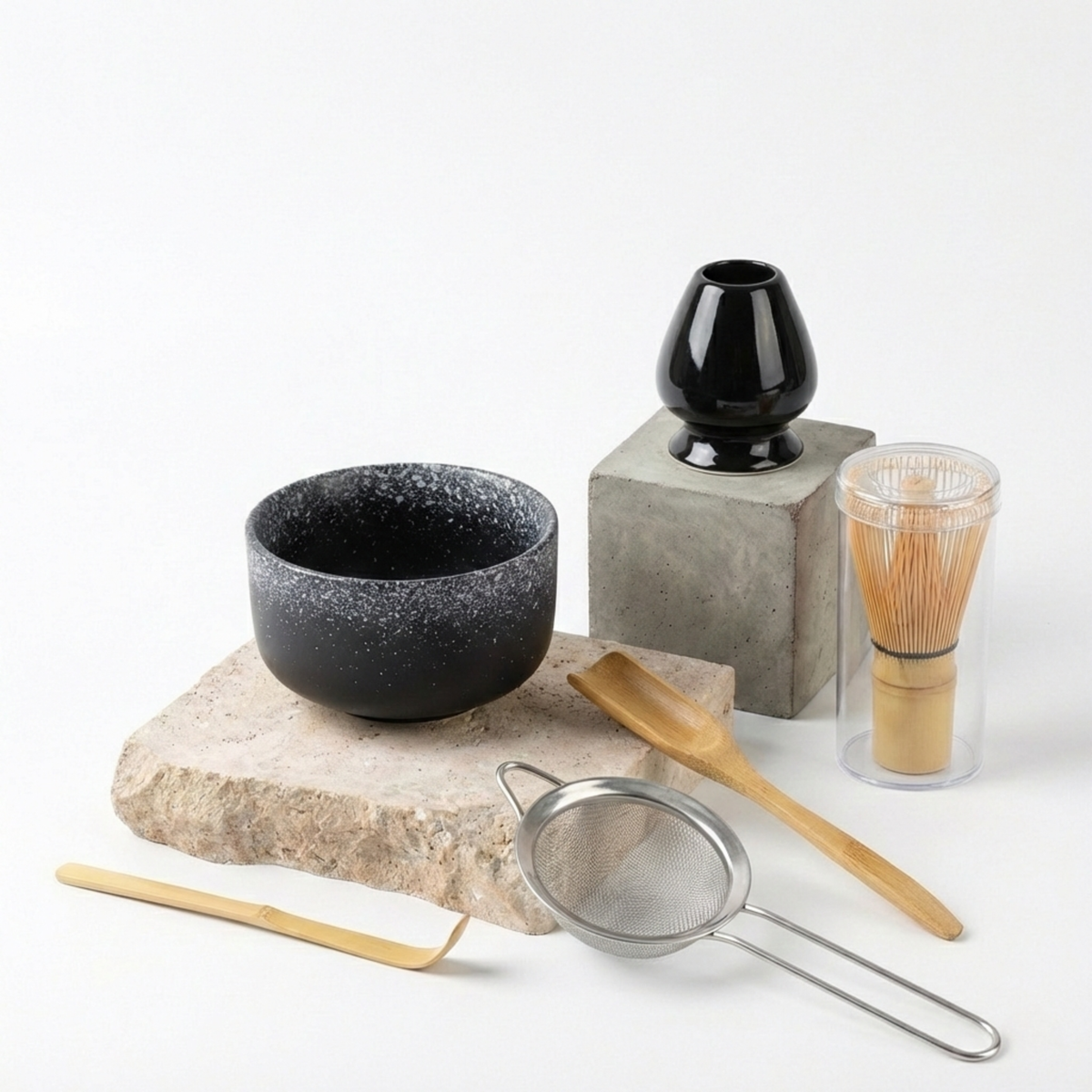 Coffret matcha composé d'un bol en céramique noire mouchetée, d'un fouet chasen en bambou, de son support, d'un tamis et de deux cuillères, sur pierre de travertin — Aoti Matcha