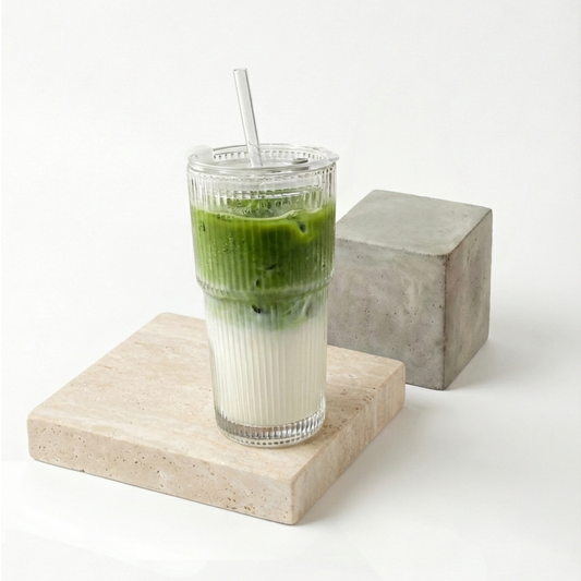 Verre strié de 600 ml empli d'un matcha latte glacé, paille de verre et couvercle posés sur travertin — Aoti Matcha