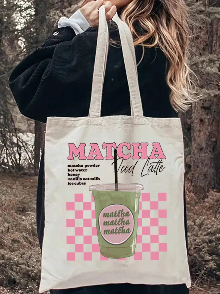 Tote bag à damier rose porté à l'épaule sur une tenue en jean, inscription Matcha Iced Latte — Aoti Matcha