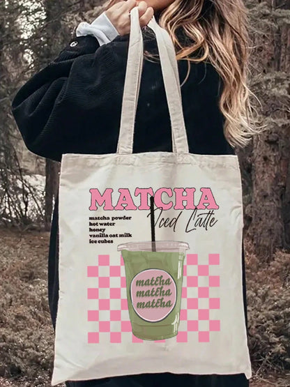 Tote bag à damier rose porté à l'épaule sur une tenue en jean, inscription Matcha Iced Latte — Aoti Matcha